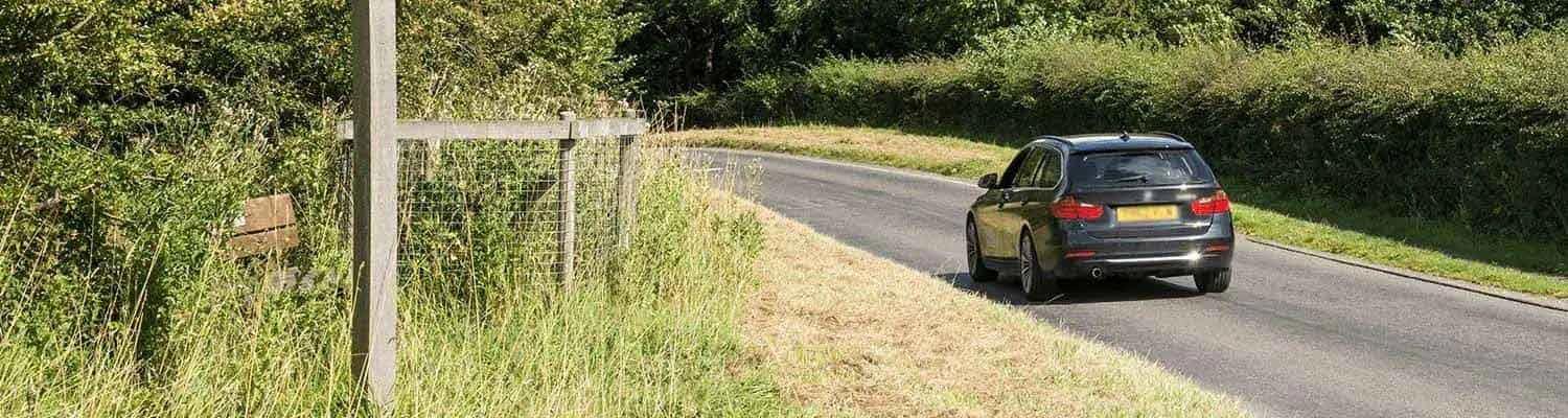 Back of a black car driving on a country road